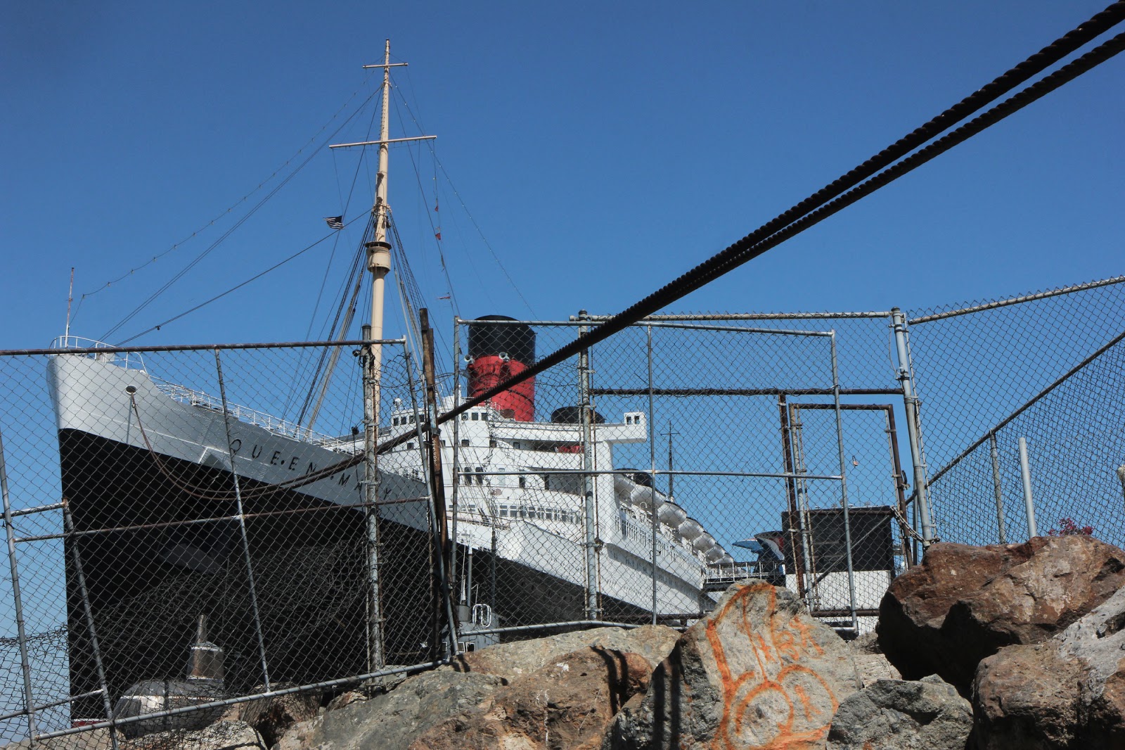 A fence keeps people off of the rocky barrier surrounding the Queen Mary in Downtown Long Beach, Thursday, June 10, 2021. Photo by Brandon Richardson.