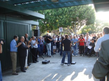 Eric Avila, one of the men subject to a recent hate-crime attack, addresses the crowd, while Mayor Bob Foster and Councilmembers Robert Garcia, Suja Lowenthal, and Gary DeLong look on.