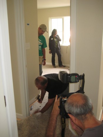 Mayor Foster installs the Lopezes carpeting while Enrique Lopez (with wife Sonia in background) looks on.