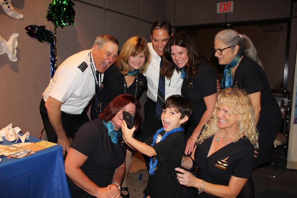 The sibling of a Miller Children’s & Women’s patient snaps a selfie with the crew of Alaska Airlines during a beach-themed bash in the hospital.