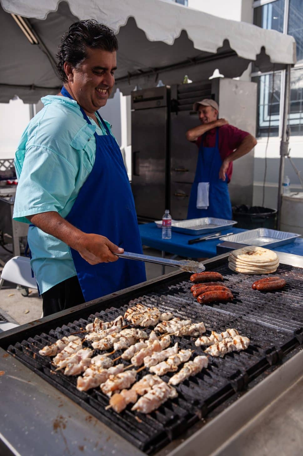 Albert Comstandime smiles as he cooks the chicken and Loukaniko at the Mezethes booth at the Greek Fest in Long Beach Sunday September 2, 2018. Photo by Kelly Smiley