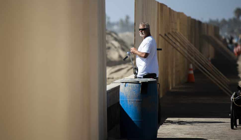 Mike Vanderipe looks at the surf between a gap of a temporary wood wall that was built in an attempt to save homes from being flooded on the Peninsula in Long Beach October 5, 2018. Photo by Thomas R Cordova.