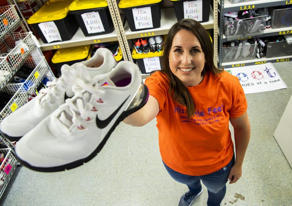 Hali Wolf, of His Little Feet, holds up a pair of shoes while in her garage where she keeps hundreds of donated shoes in Long Beach. Photo by Thomas R Cordova.