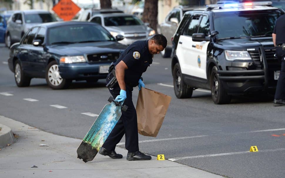 Long Beach Police take a broken skateboard and a shoe into evidence, at the scene of a crash, where a skateboarder was struck by a vehicle at the intersection of Bellflower Boulevard and 27th Street Tuesday. Nov. 27, 2018. Photo by Stephen Carr.